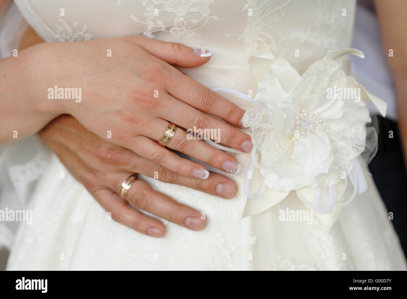 Les mains des mariés avec des anneaux sur une robe blanche Banque D'Images