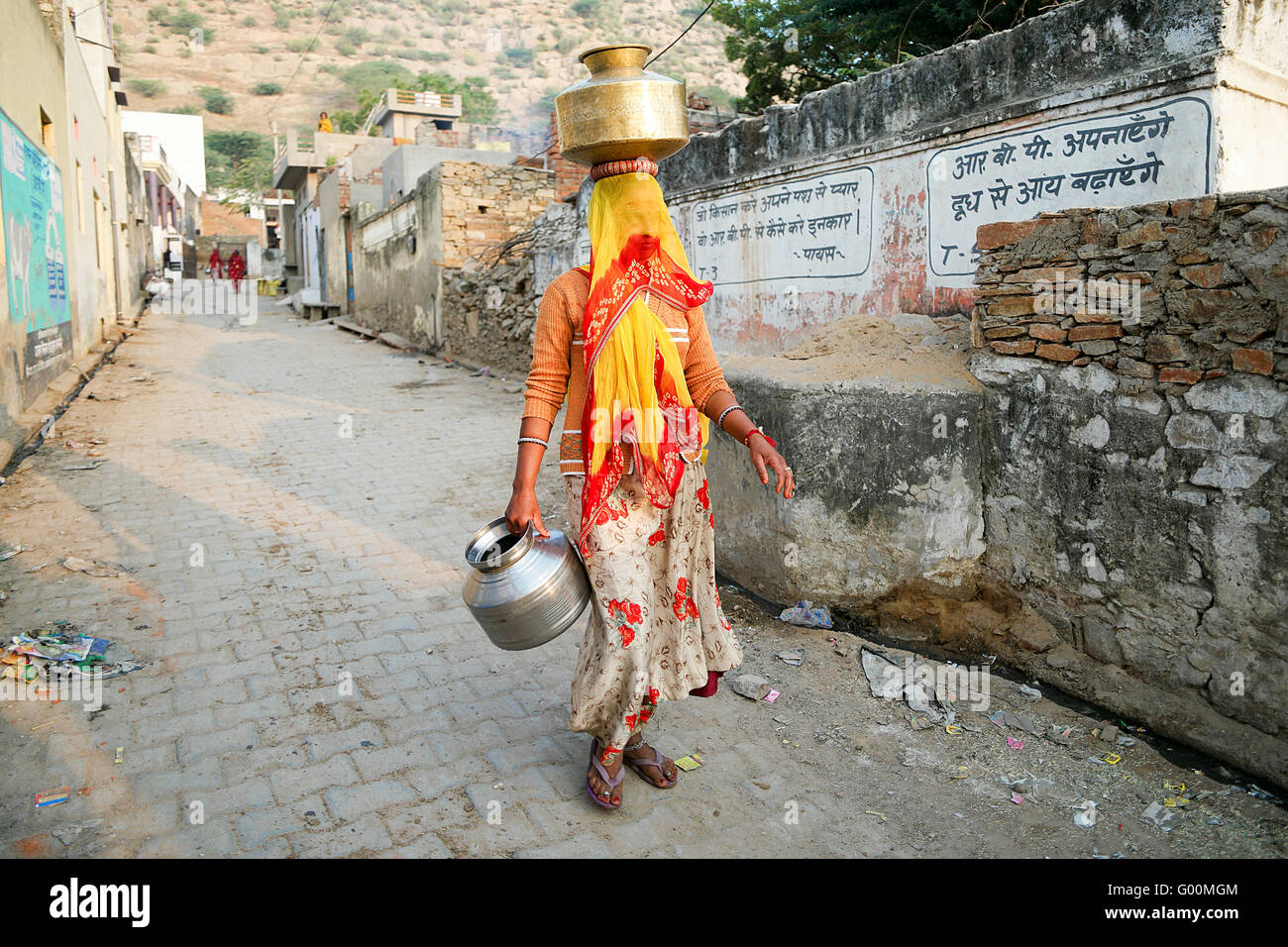 Les femmes indiennes locales portant un seau d'eau dans les rues de Pushkar. Banque D'Images