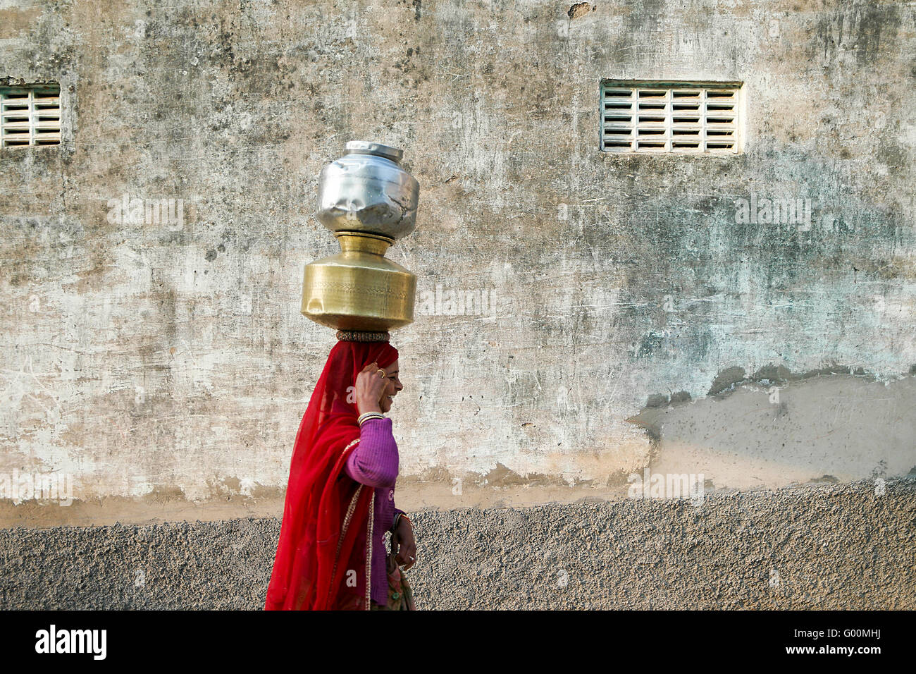 Les femmes indiennes locales portant un seau d'eau dans les rues de Pushkar. Banque D'Images