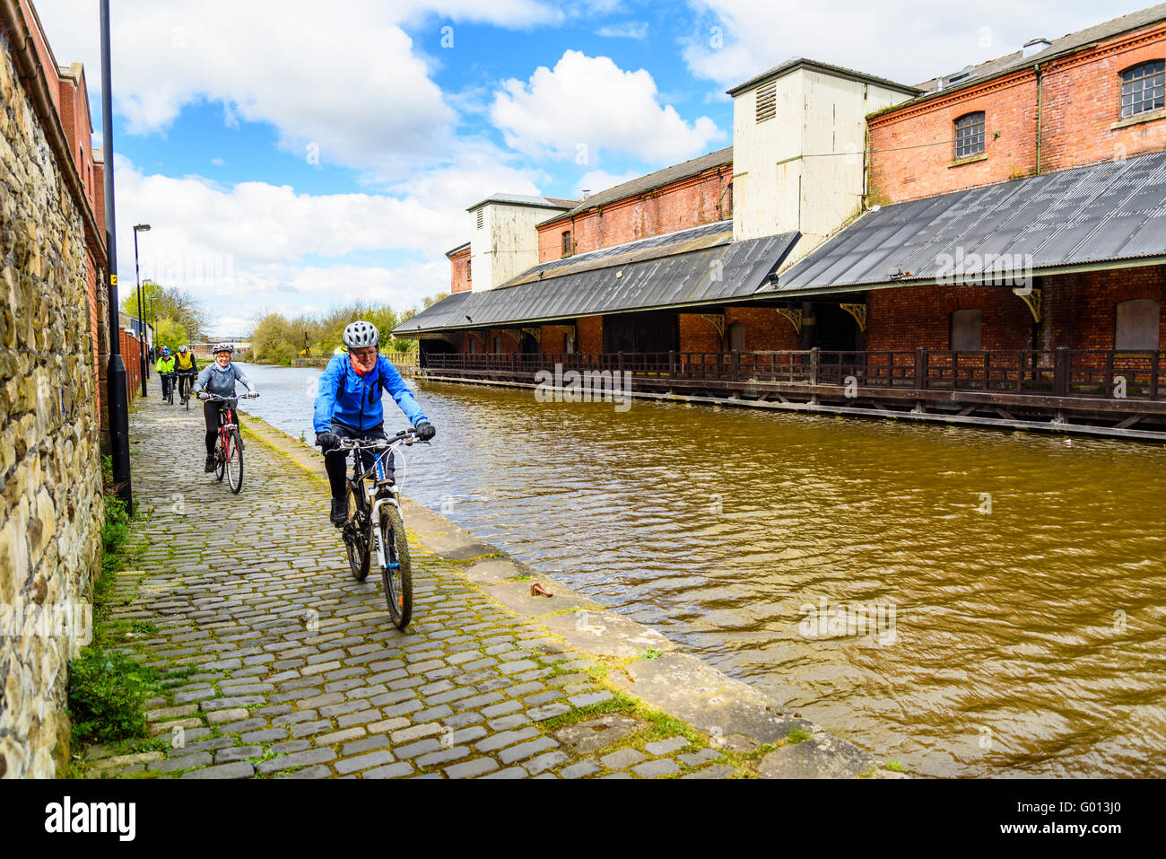 Les cyclistes sur chemin de halage du canal en face de Leeds et Liverpool Wigan Pier à Wigan Greater Manchester UK Banque D'Images