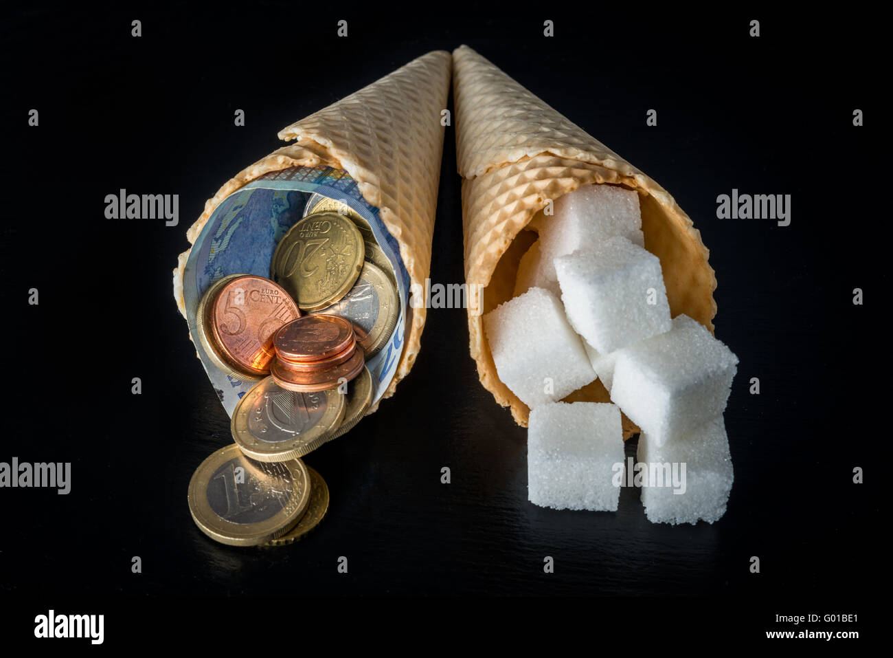 Cônes gaufrette avec des morceaux de sucre dans l'un et de l'argent (billets et pièces en euro cents) symbolisant l'impôt sur le sucre dans l'UE Banque D'Images