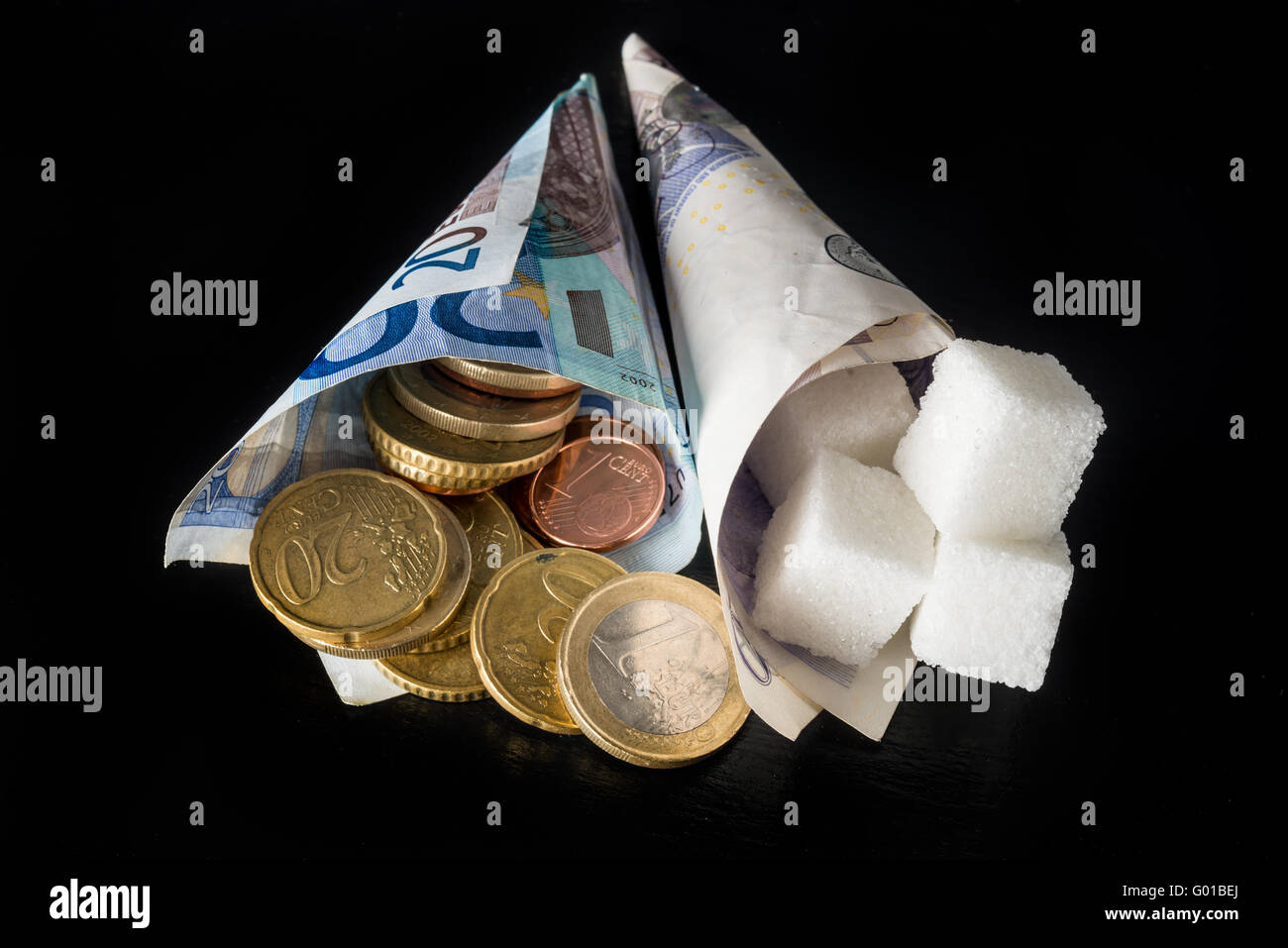 Cônes de papier avec des morceaux de sucre dans l'un et de l'argent (euro et livre des notes et pièces euro cents) symbolisant l'impôt sur le sucre dans l'UE Banque D'Images