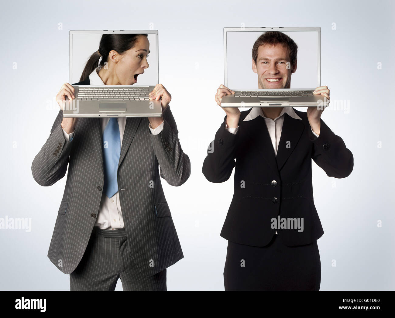 Un mâle et femelle avec têtes échangés sur leurs ordinateurs portables Banque D'Images