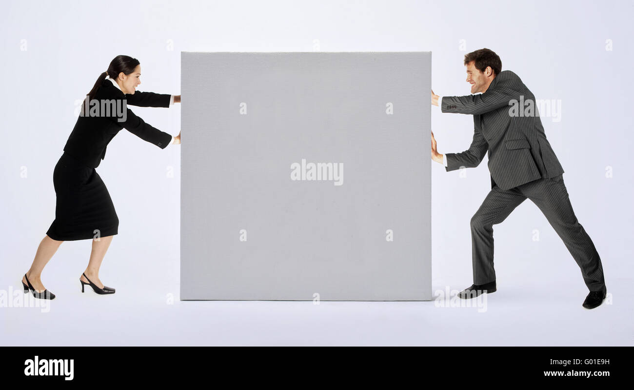 Un homme d'affaires et la femme poussant contre un blank sign. Banque D'Images