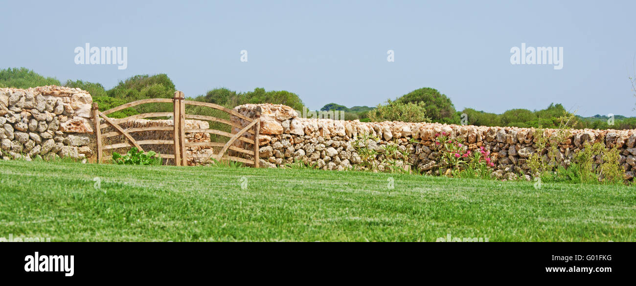 Menorca, Minorque : une barrière en bois, pelouse et mur de pierre dans la campagne minorquine Banque D'Images