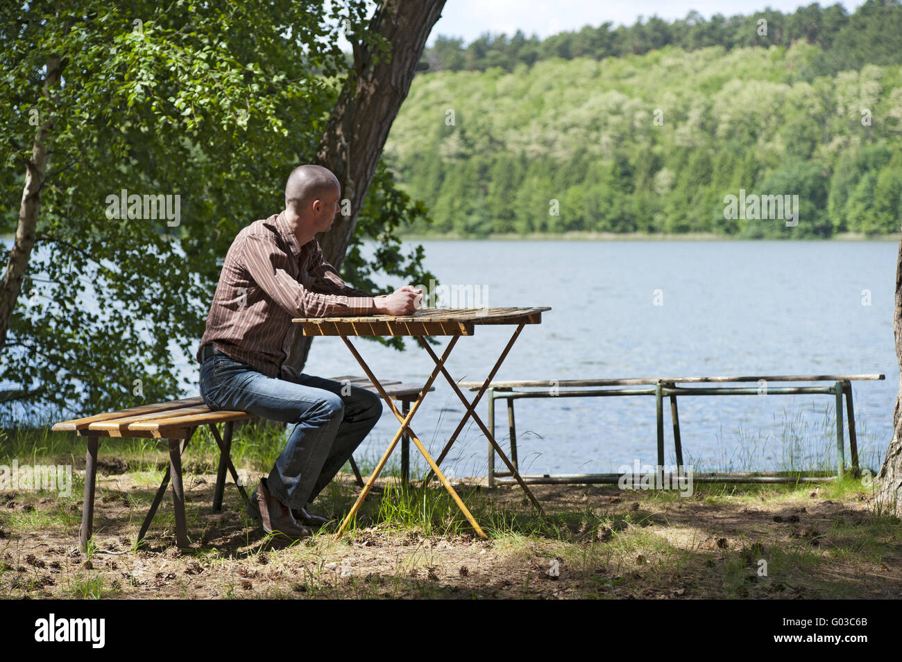 Jeune homme est assis sur les rives du lac de la forêt Banque D'Images
