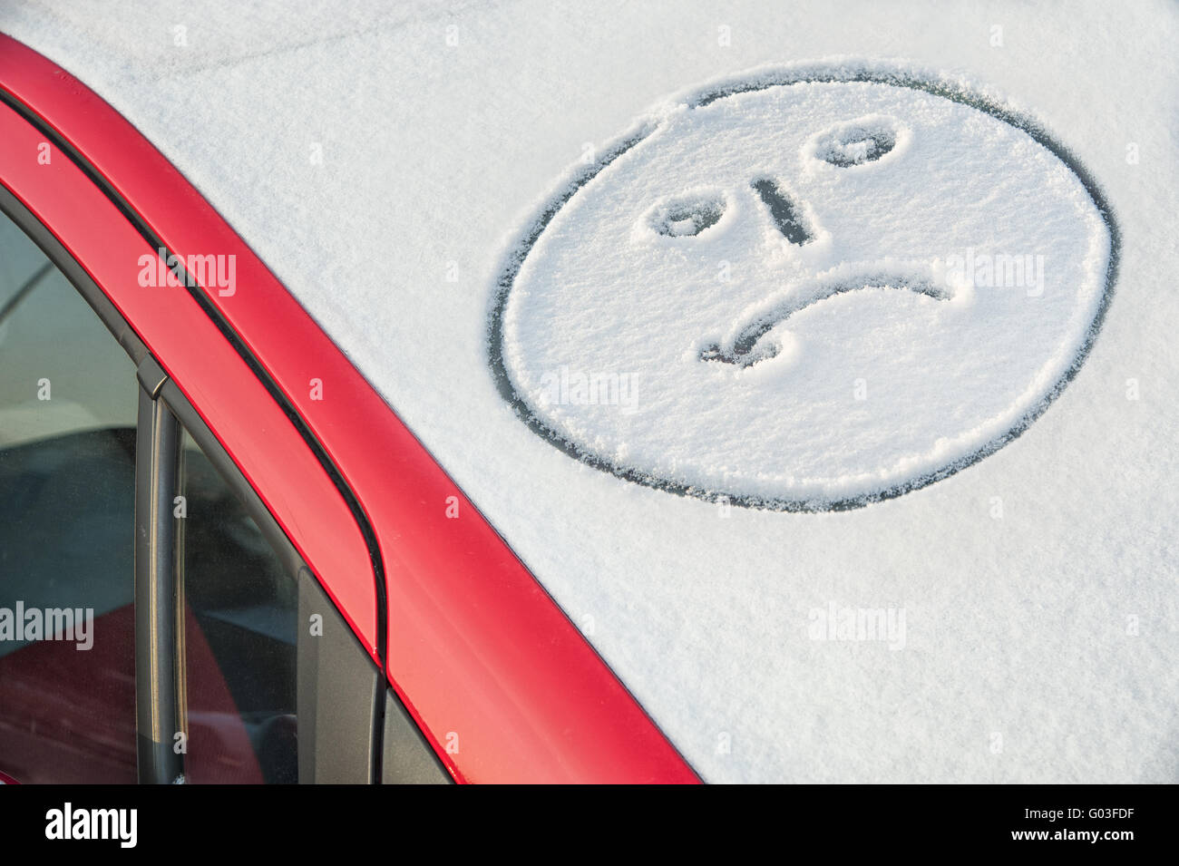 Visage en pleurs sur le pare-brise d'une voiture enneigée Banque D'Images