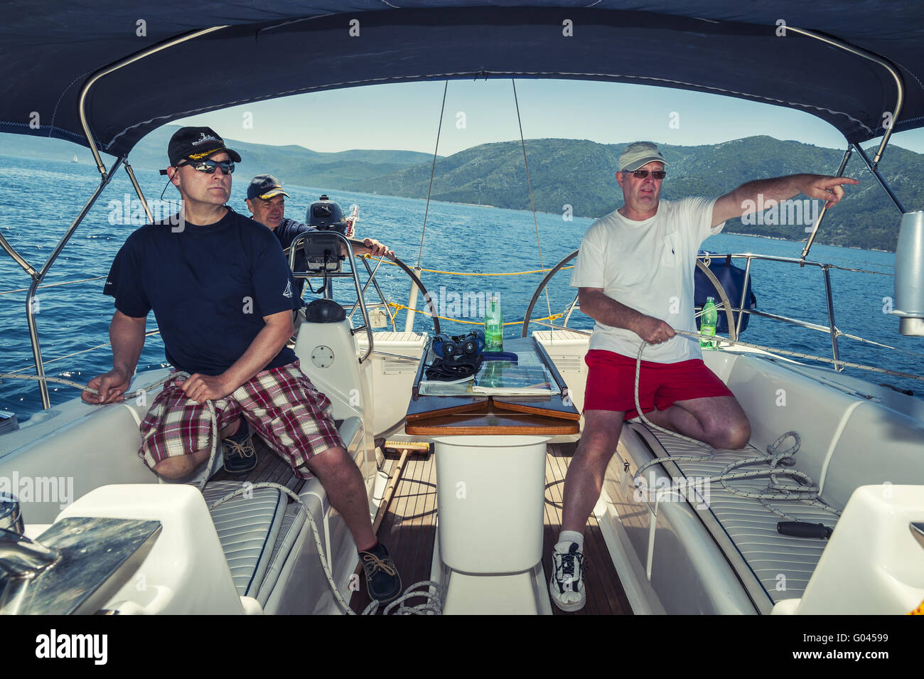 3 hommes d'équipage à l'arrière d'un bateau à leur yacht o Banque D'Images