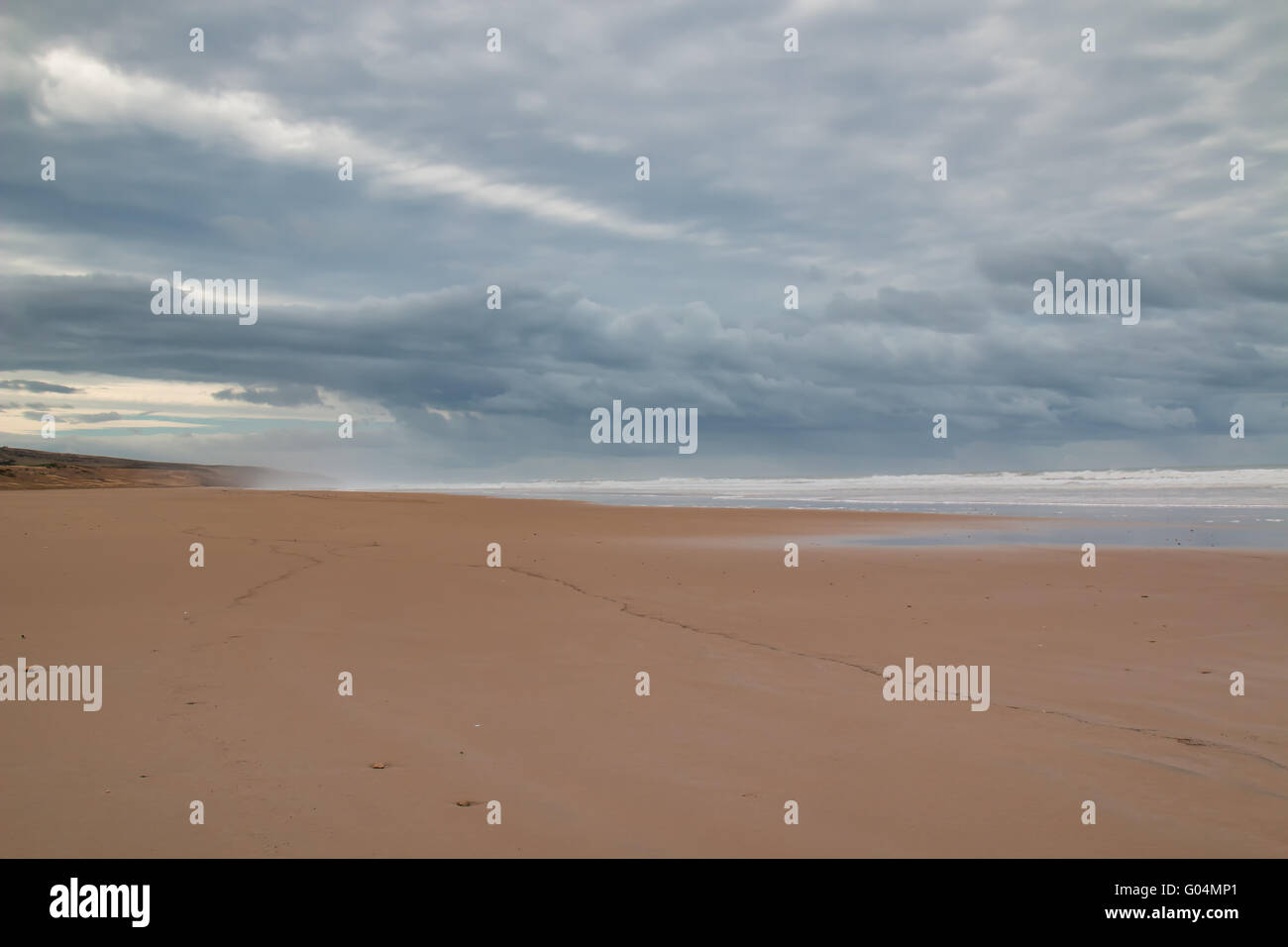 Le temps orageux avec de gros nuages. Plage avec une eau ondulée de l'océan Atlantique au cours d'une marée. Montagne dans l'arrière-plan. Banque D'Images