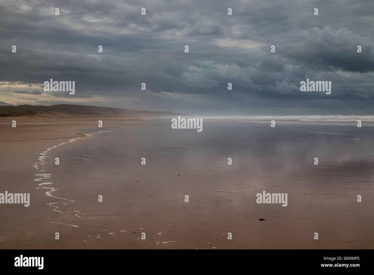 Le temps orageux avec de gros nuages. Plage avec une eau ondulée de l'océan Atlantique au cours d'une marée. Montagne dans l'arrière-plan. Banque D'Images