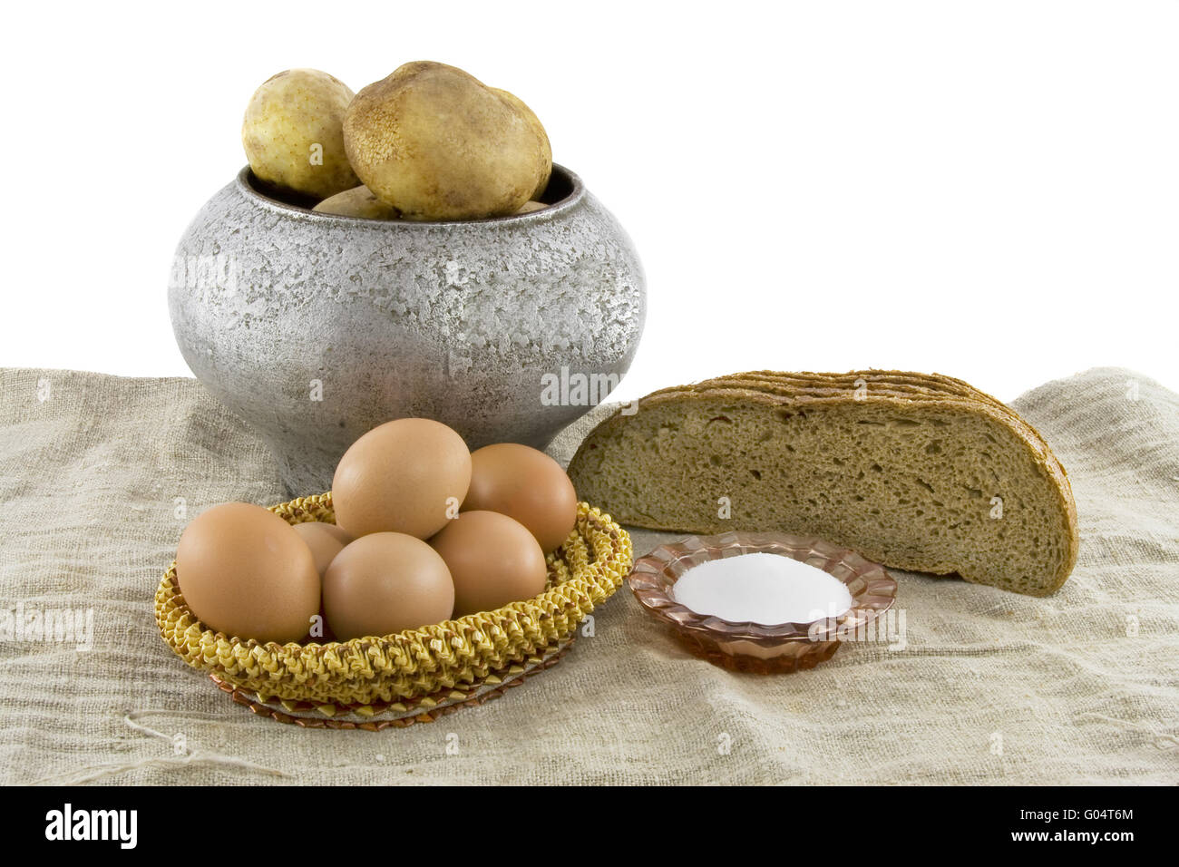 La nature morte à partir de la nourriture végétarienne. Oeufs frais couché dans un petit panier caronculée, parfumé d'un pain de seigle, pommes de terre bouillies dans une fonte k Banque D'Images