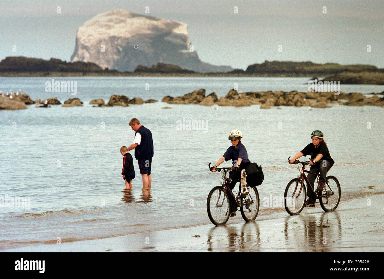 Les cyclistes sur plage, avec bass rock derrière. North Berwick, East Lothian, Scotland Banque D'Images