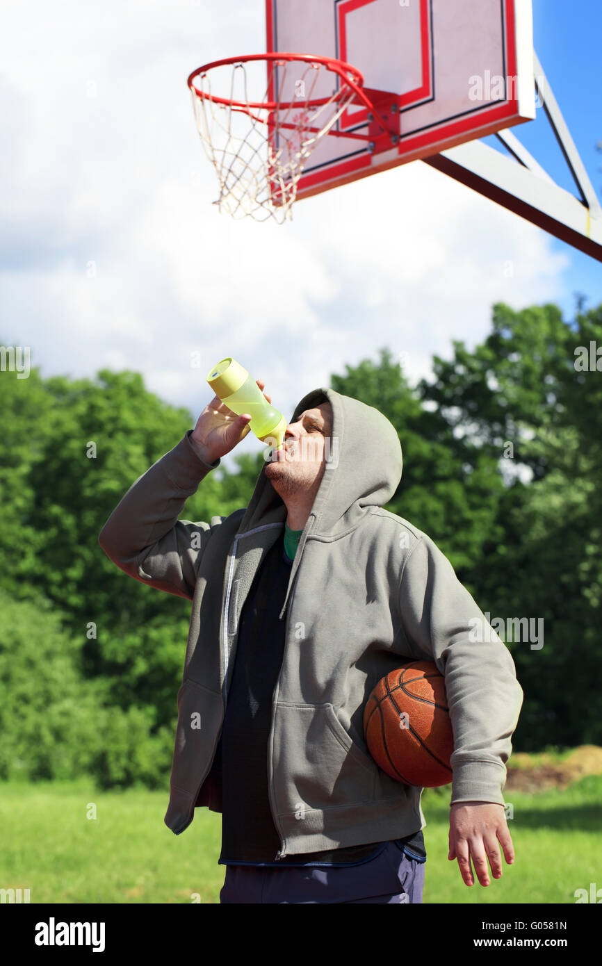 Man holding basket-ball et le verre bouteille de w Banque D'Images
