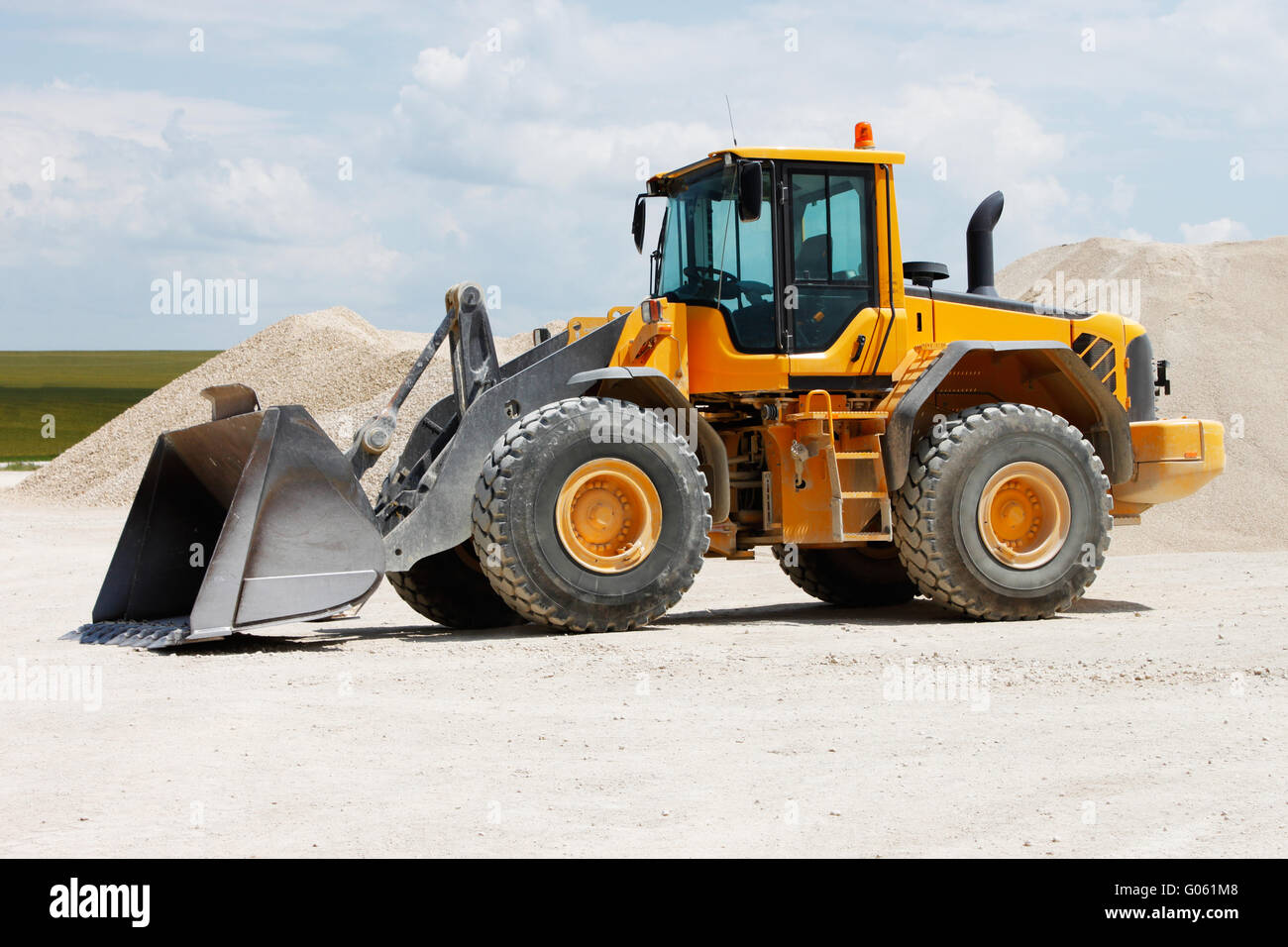 Excavatrice jaune sur un site de construction contre le ciel bleu Banque D'Images