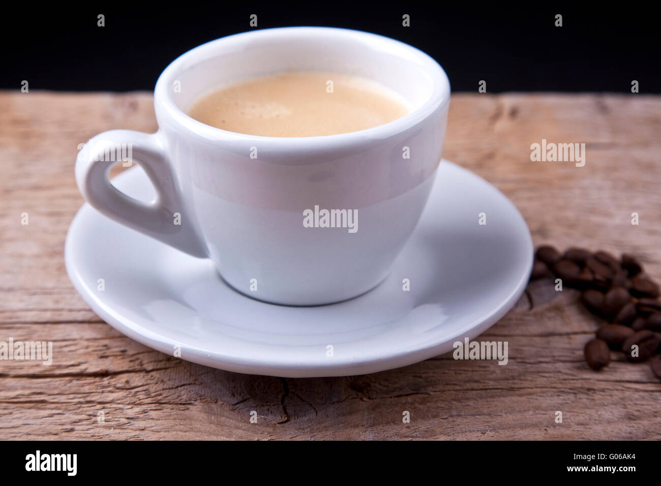 Café chaud dans la tasse blanche cappuchino sur table en bois avec des haricots Banque D'Images