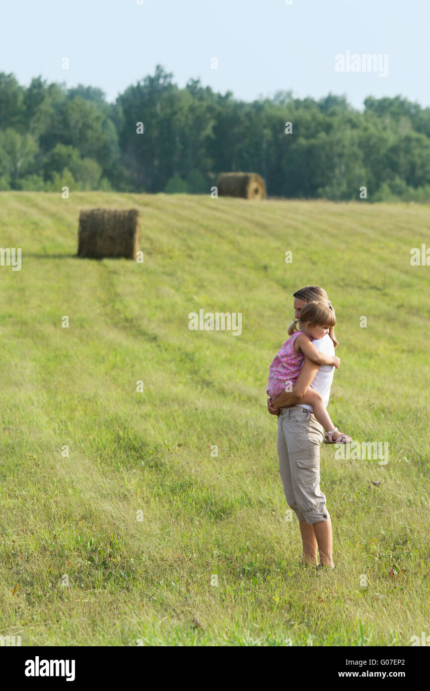 La fille s'assied à mère sur les mains. À l'extérieur. Banque D'Images