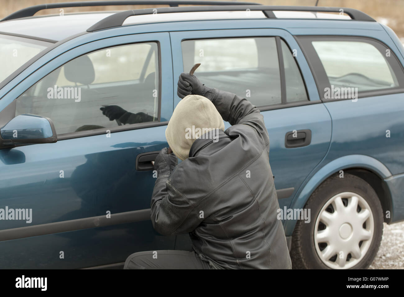 Voleur avec un pied-de-biche en essayant d'ouvrir la porte de la voiture Banque D'Images