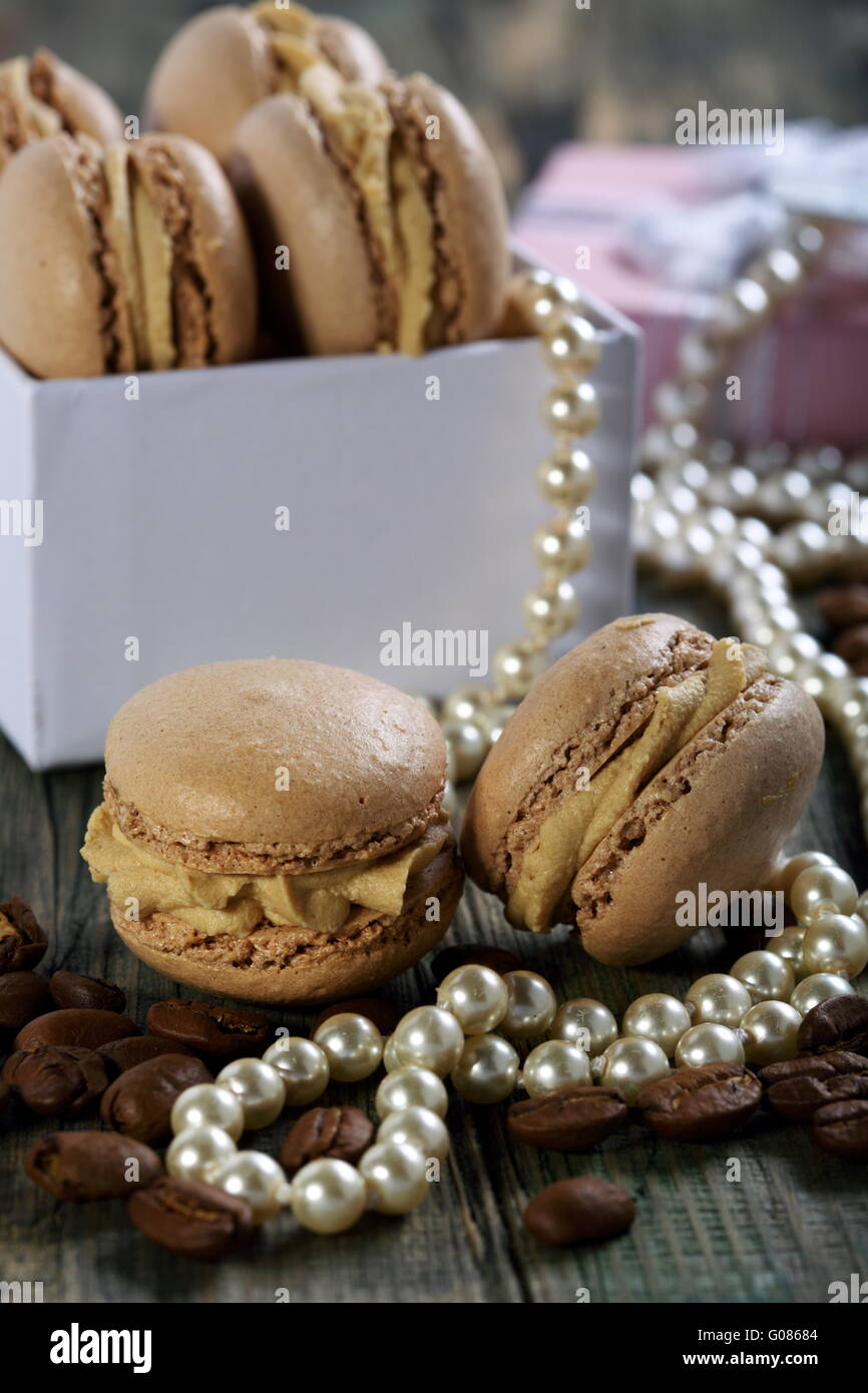 Les macarons dans la boîte, les perles et les grains de café. Banque D'Images