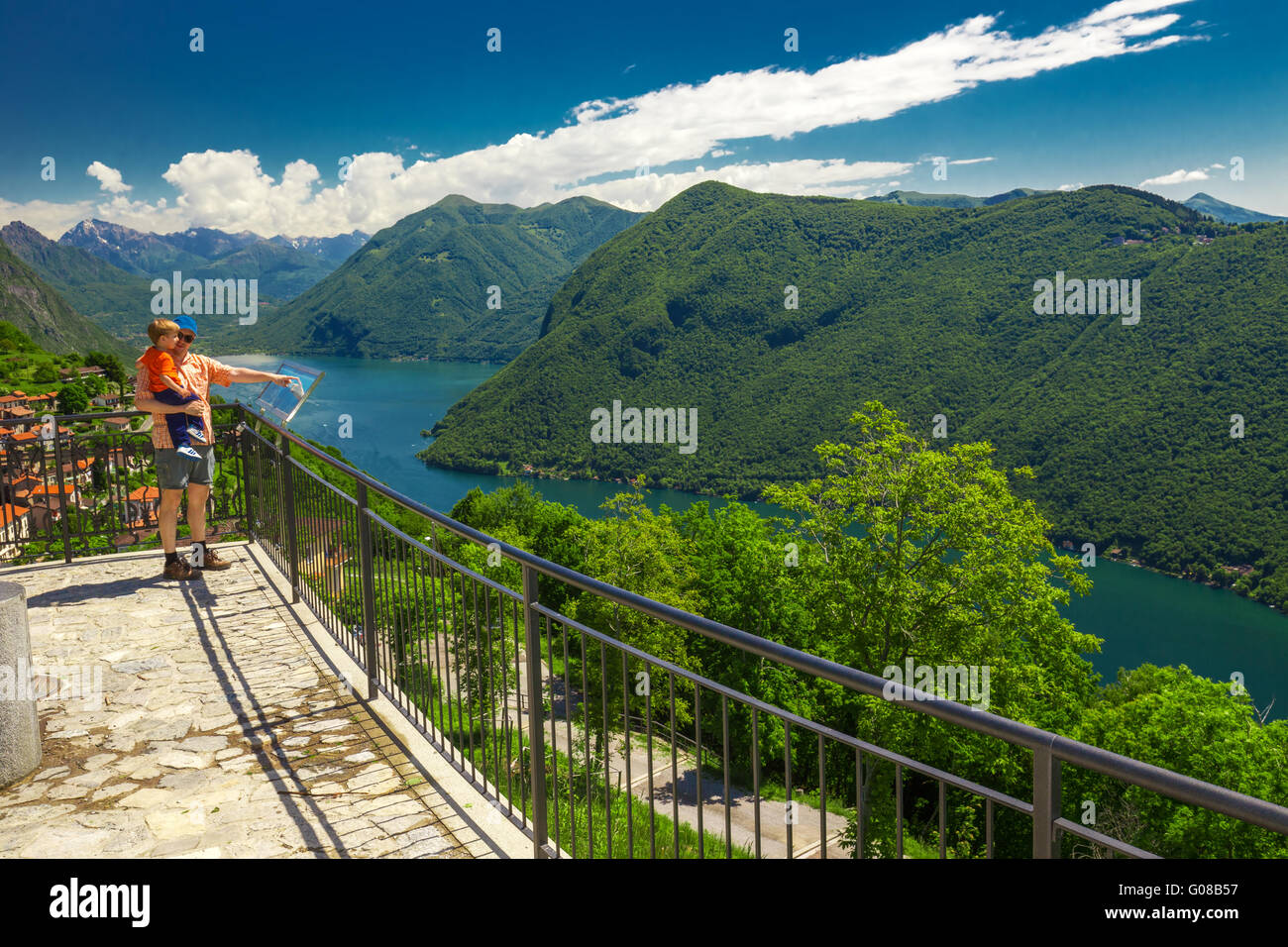 Père se dirigeant à la carte et d'expliquer son petit-fils l'emplacement de lac de Lugano et les Alpes suisses depuis le Monte Bre, Tichino, Suisse Banque D'Images