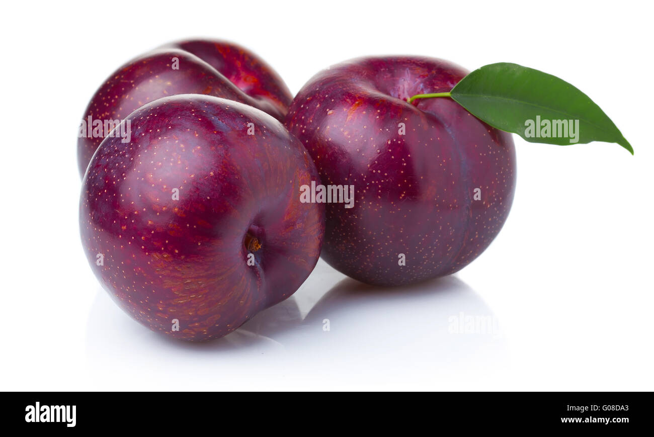 Trois fruits mûrs de prune violet vert avec des feuilles isolées Banque D'Images