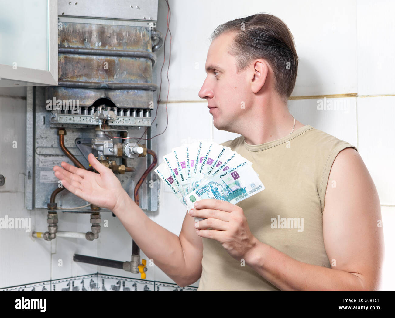 L'homme compte de l'argent pour la réparation d'un chauffe-eau à gaz Banque D'Images