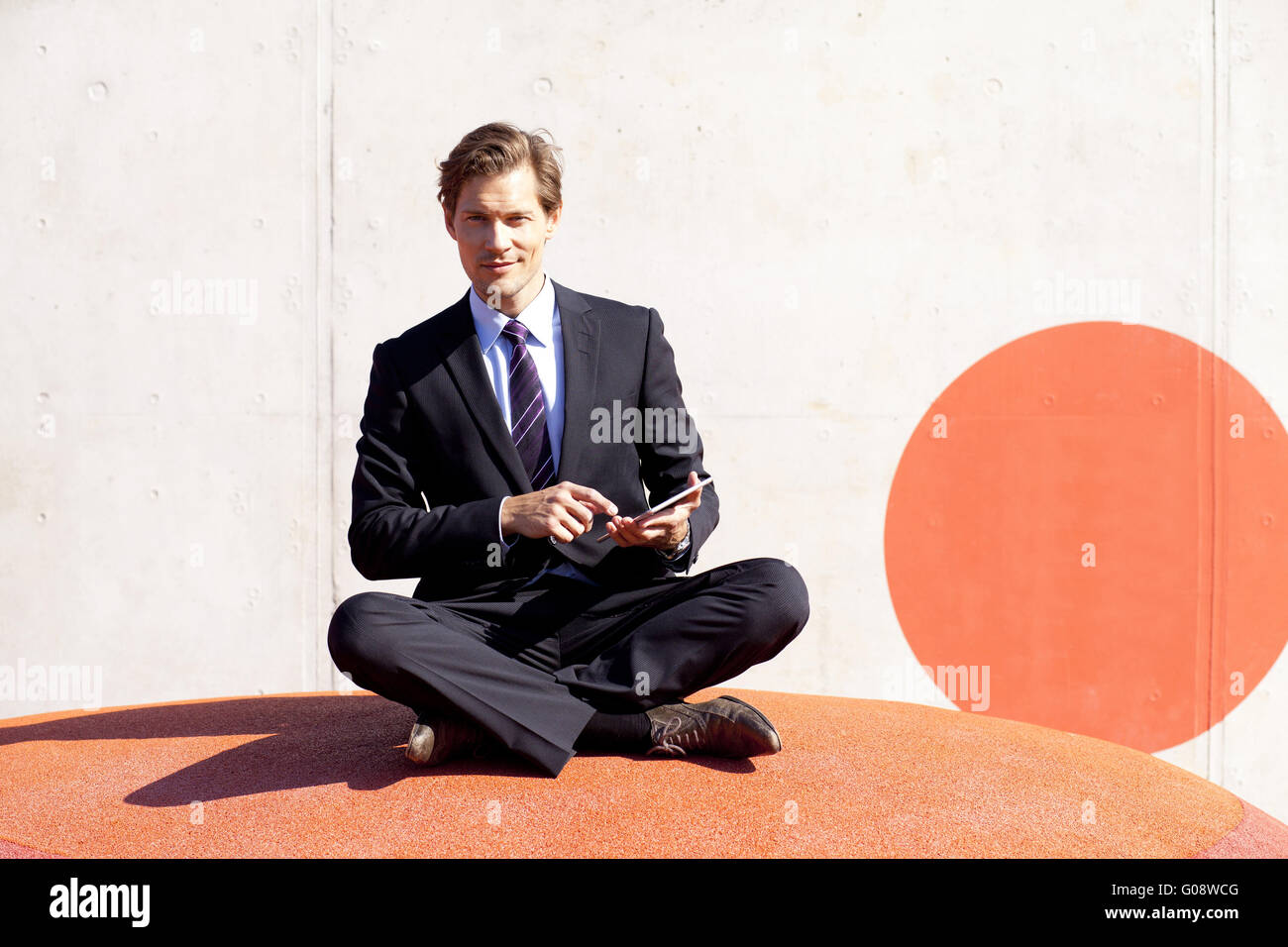 Businessman sitting cross-legged using tablet Banque D'Images