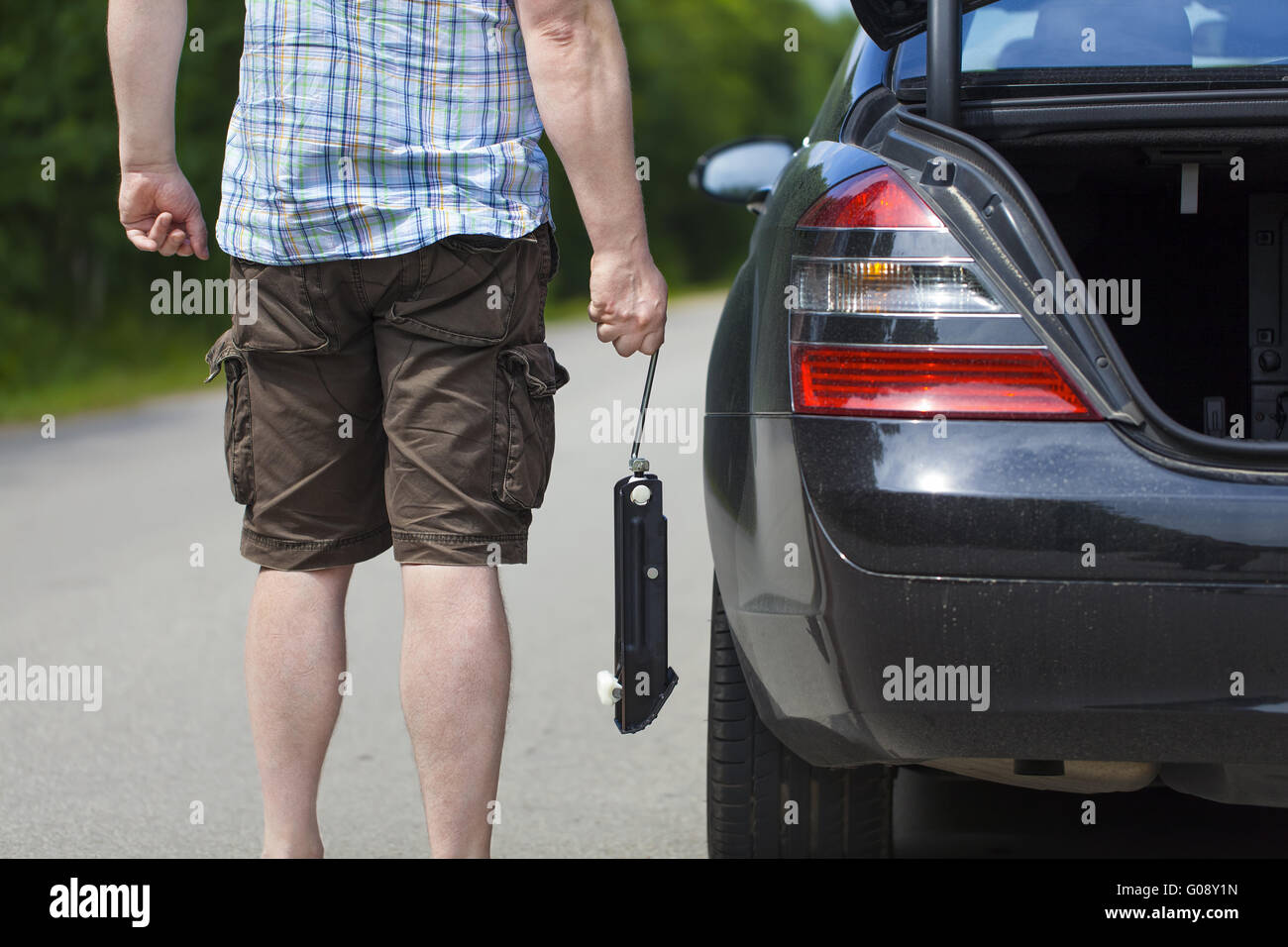 Homme avec prise à proximité de voiture sur la route Banque D'Images