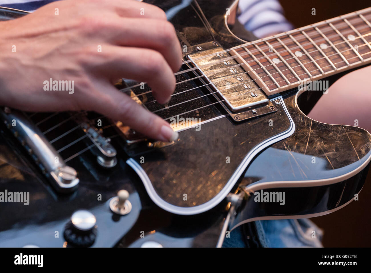 Homme pinçant les cordes sur une guitare électrique Banque D'Images
