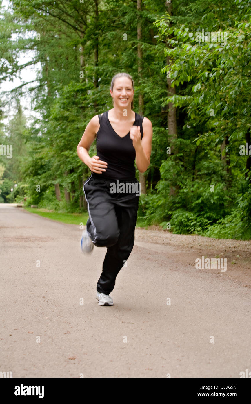Jeune femme sportive fonctionnant sur une route forrest Banque D'Images