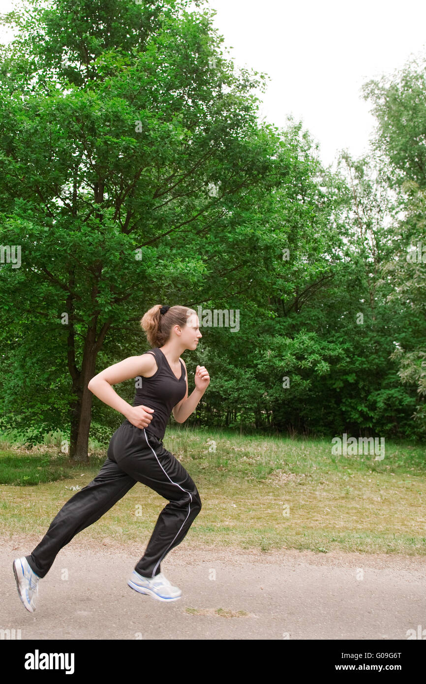 Jeune femme sportive fonctionnant sur une route forrest Banque D'Images