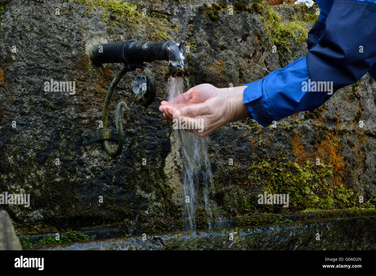 Personne actualise lui-même à une source d'eau potable Banque D'Images