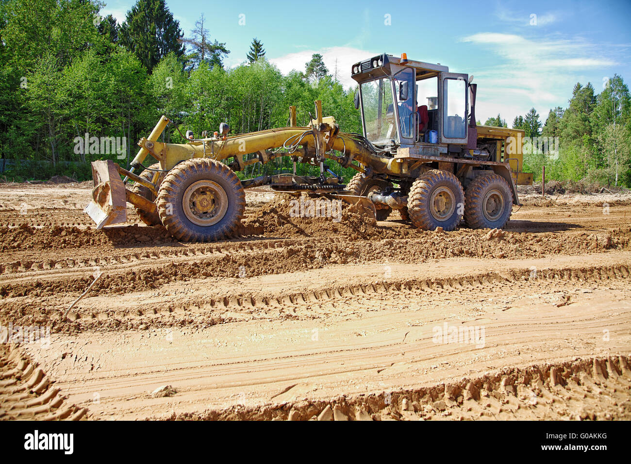 La niveleuse élimine un terrain dans l'après-midi Banque D'Images