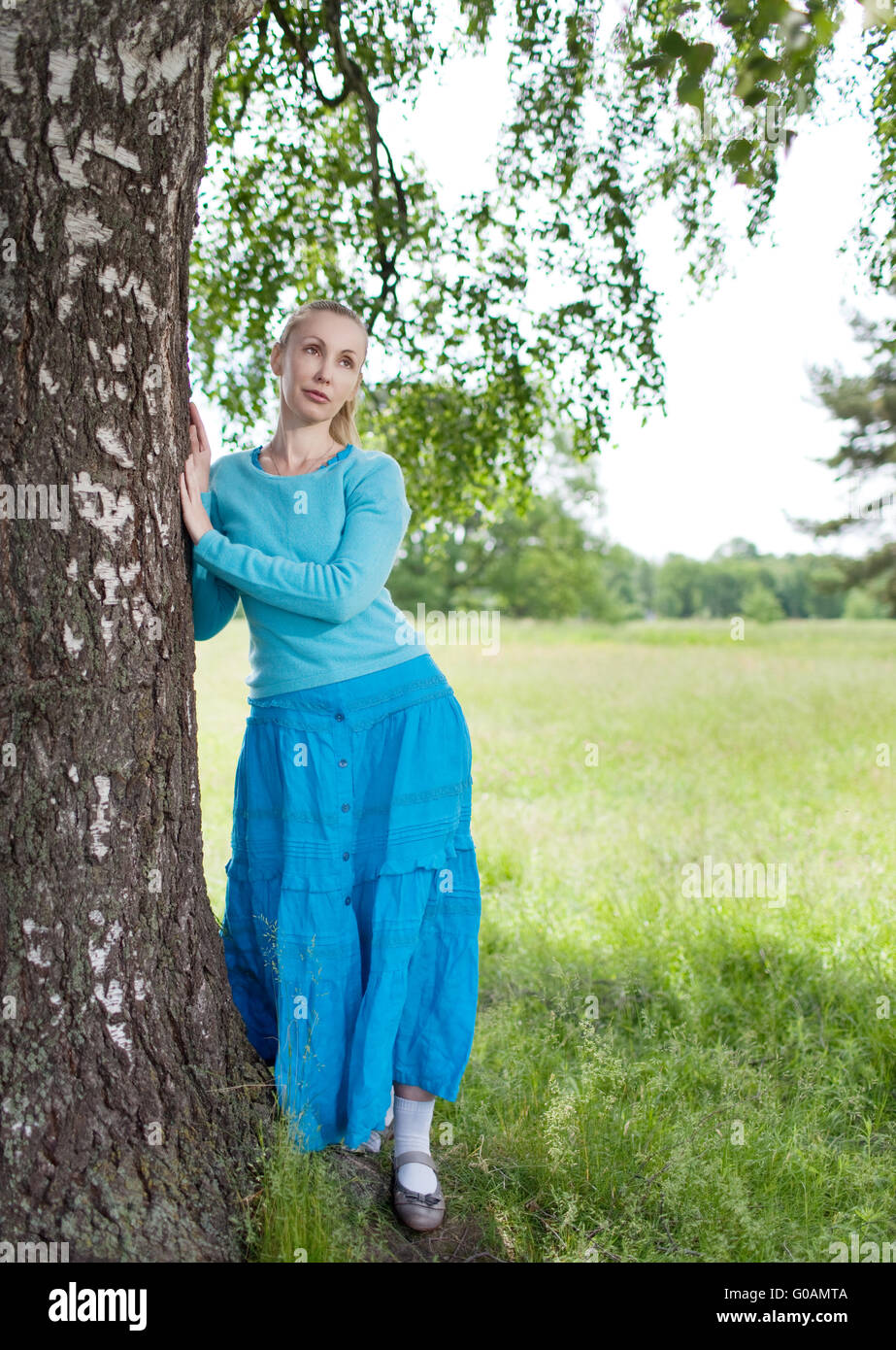 Jeune femme dans une robe bleue sur le terrain à un birc Banque D'Images