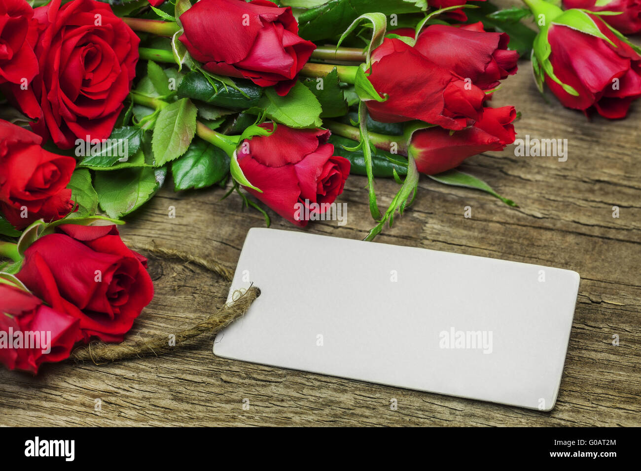 Bouquet de roses rouges avec une feuille blanche sur bois Banque D'Images