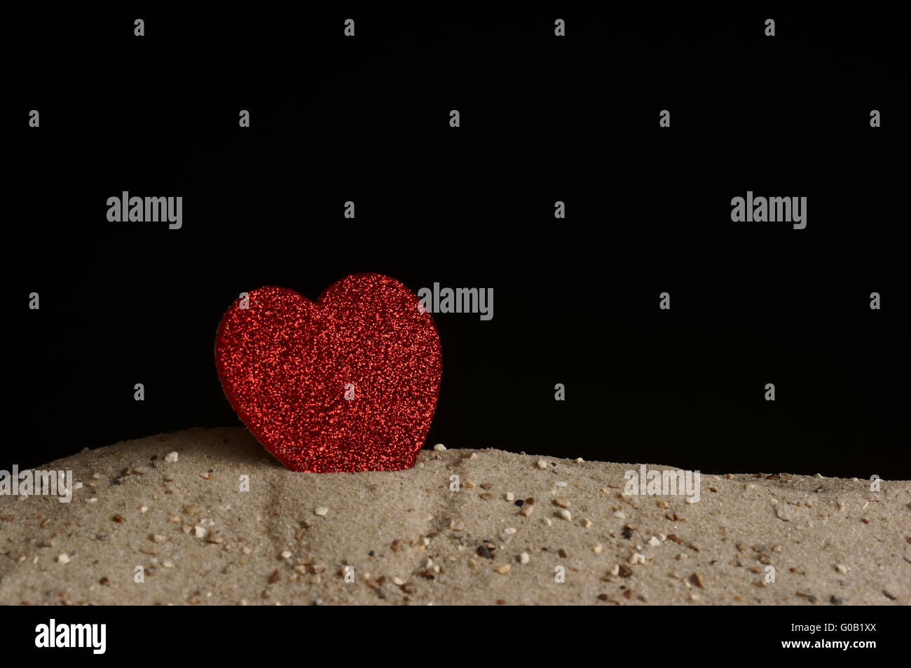 Coeur debout dans le sable en face de la zone noire Banque D'Images