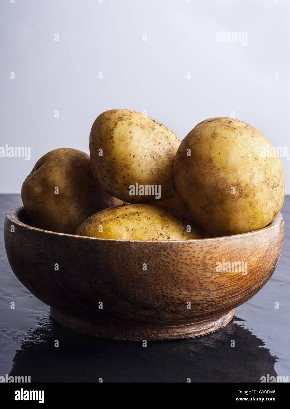 Les pommes de terre crues dans un bol sur la table en pierre Banque D'Images