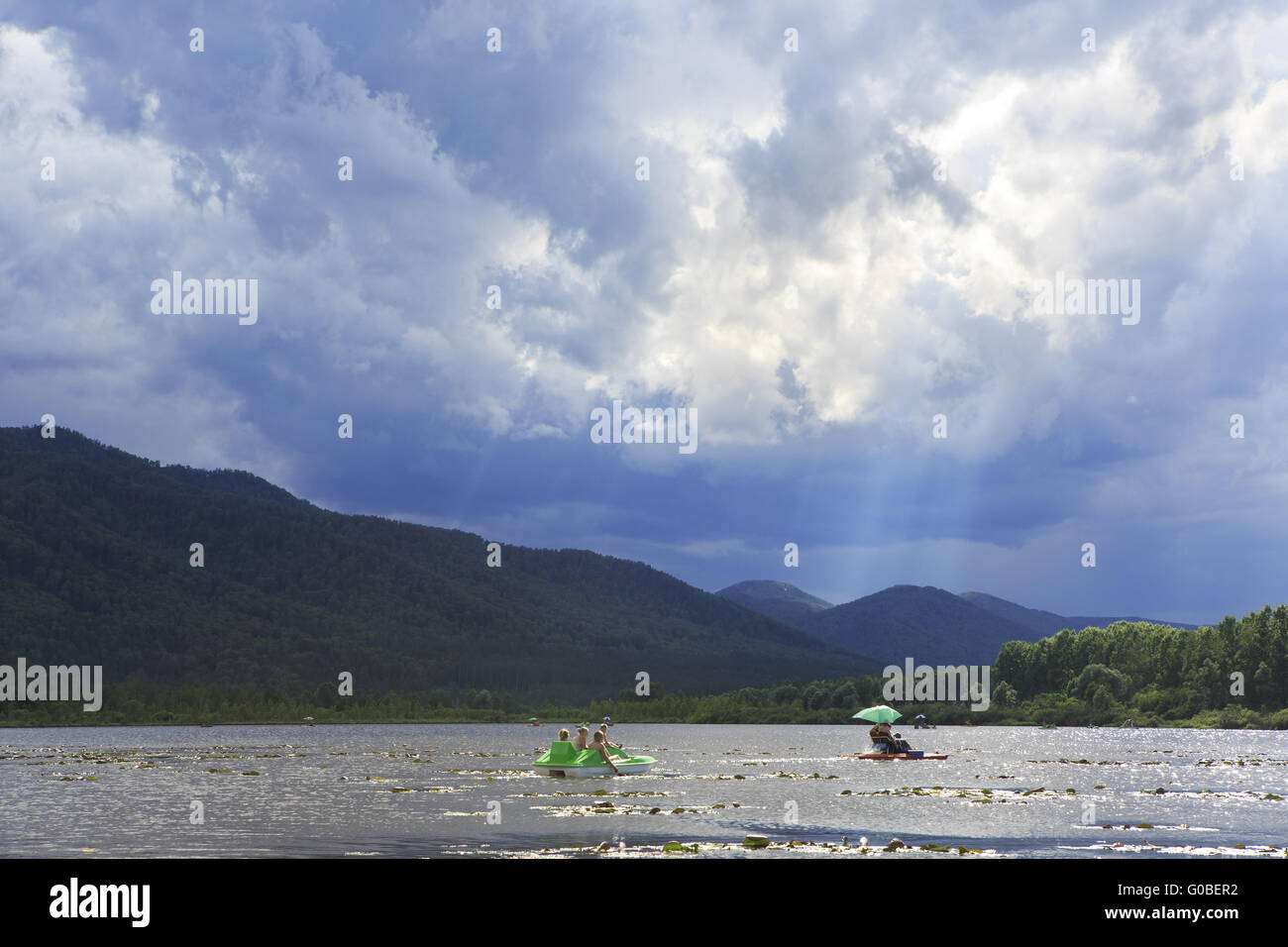 Rayons de soleil percent les nuages de tempête sur le lac de montagne Manzherok. Banque D'Images