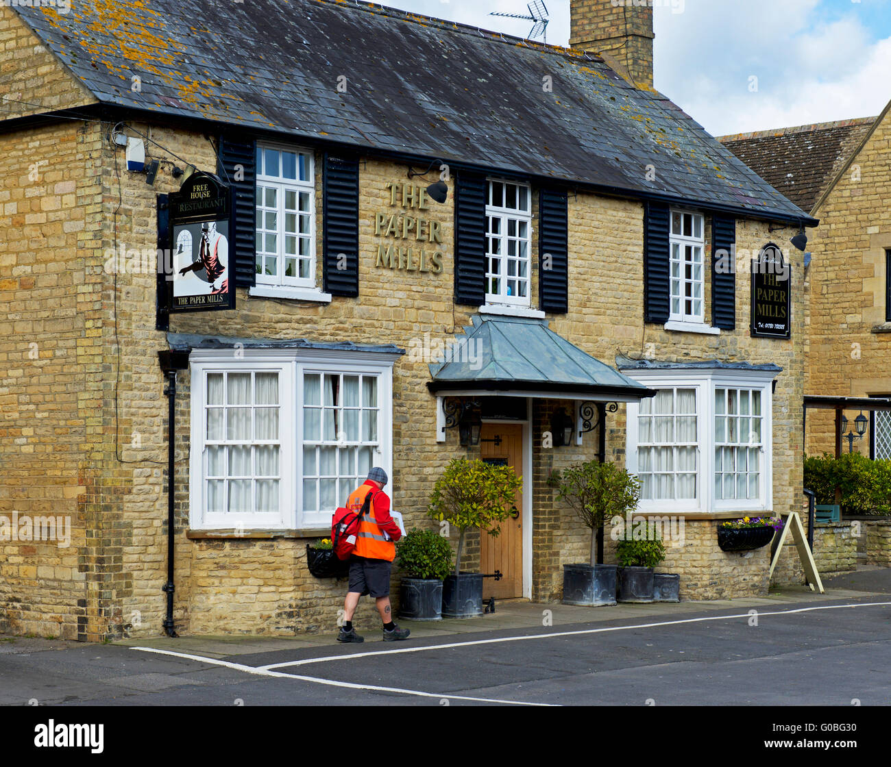 Postman remettant au Papiers pub dans le village de Wansford, Cambridgeshire, Angleterre, Royaume-Uni Banque D'Images
