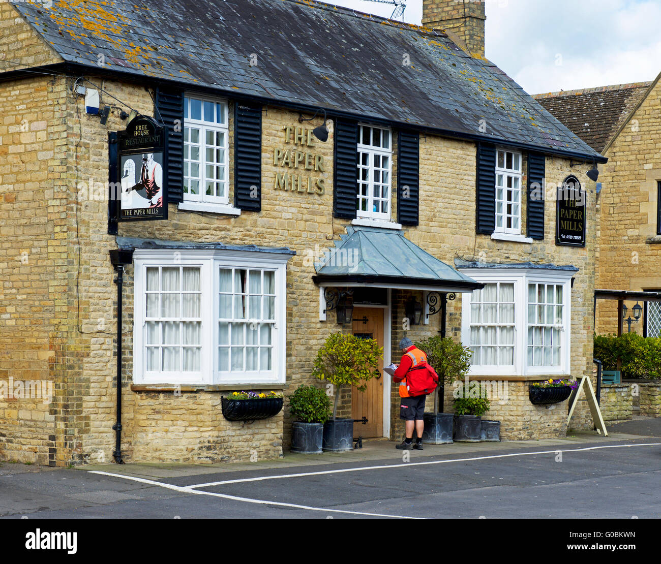 Postman remettant au Papiers pub dans le village de Wansford, Cambridgeshire, Angleterre, Royaume-Uni Banque D'Images