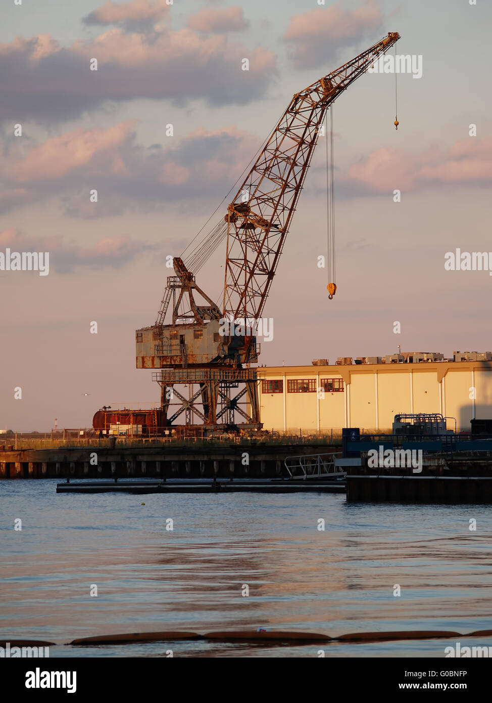 Grue portuaire gris rouillé contre Ciel nuageux Banque D'Images