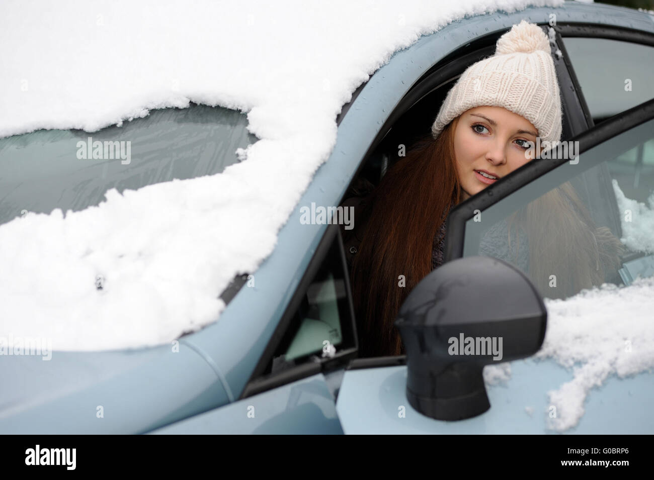 Jeune femme dans une voiture enneigée Banque D'Images