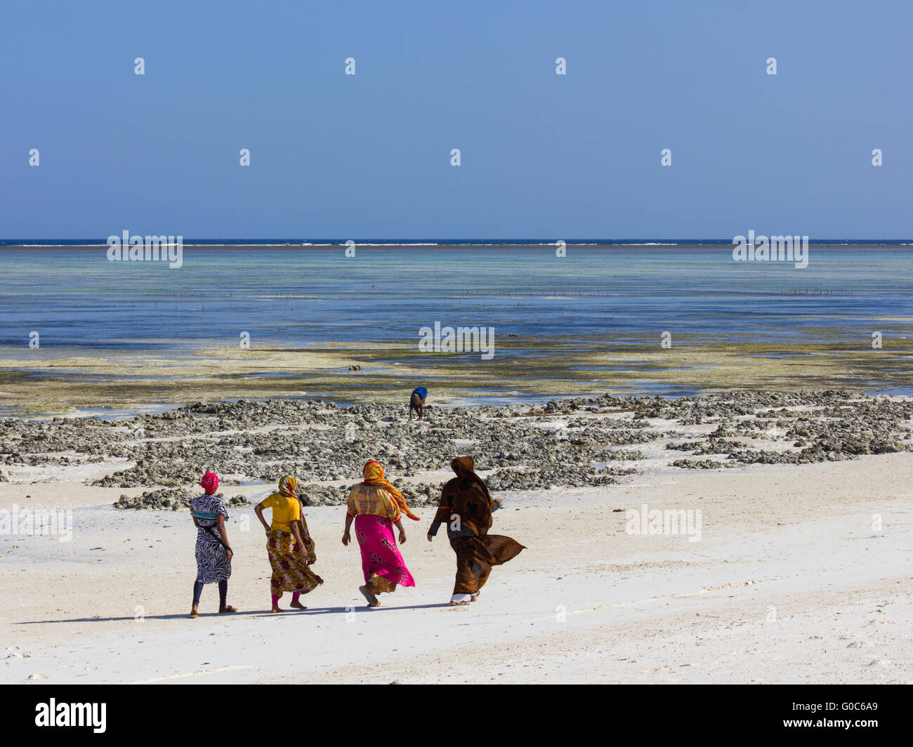 Quatre femmes musulmanes locales promenade sur la plage en costume traditionnel à makunduchi beach, zanzibar Banque D'Images