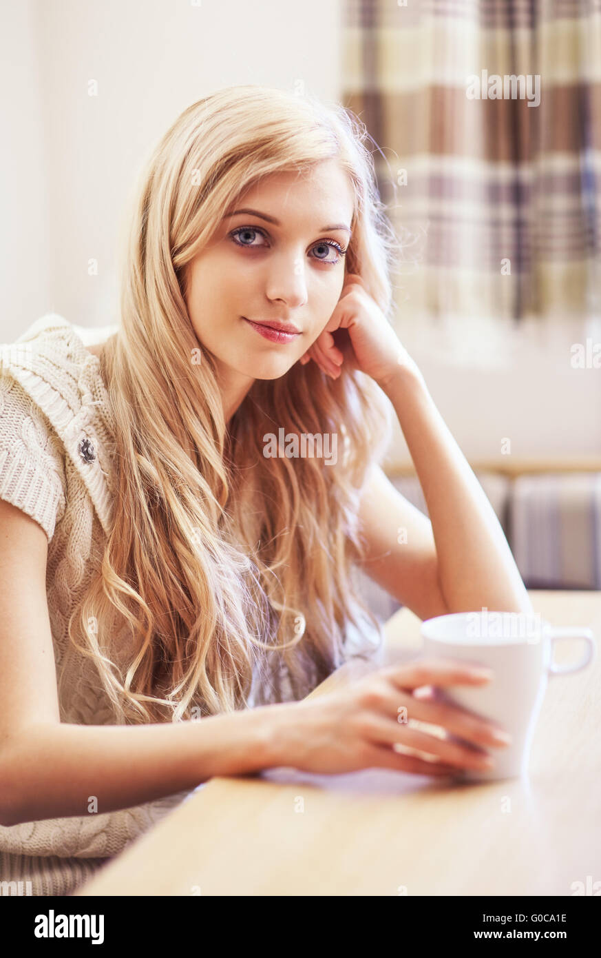 Jeune femme blonde avec une tasse à café à la table Banque D'Images