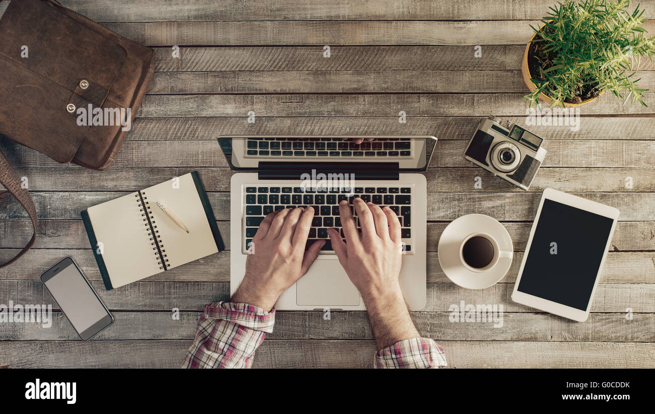 Bureau en bois vintage hippie top view, homme hands typing on a laptop Banque D'Images