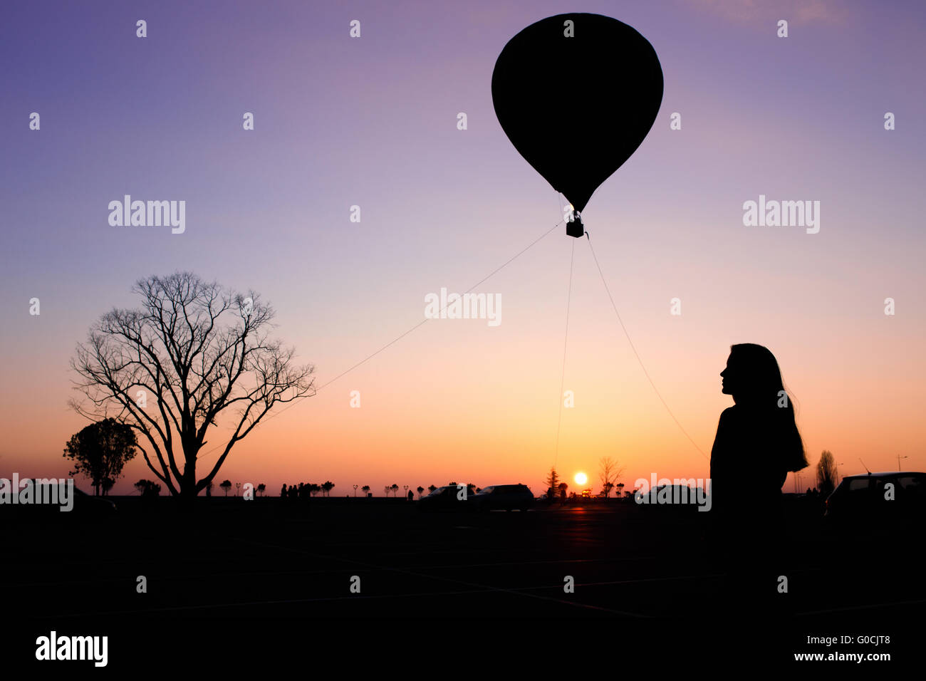 Silhouette de la jeune fille, arbre et ballon sur le coucher du soleil Banque D'Images