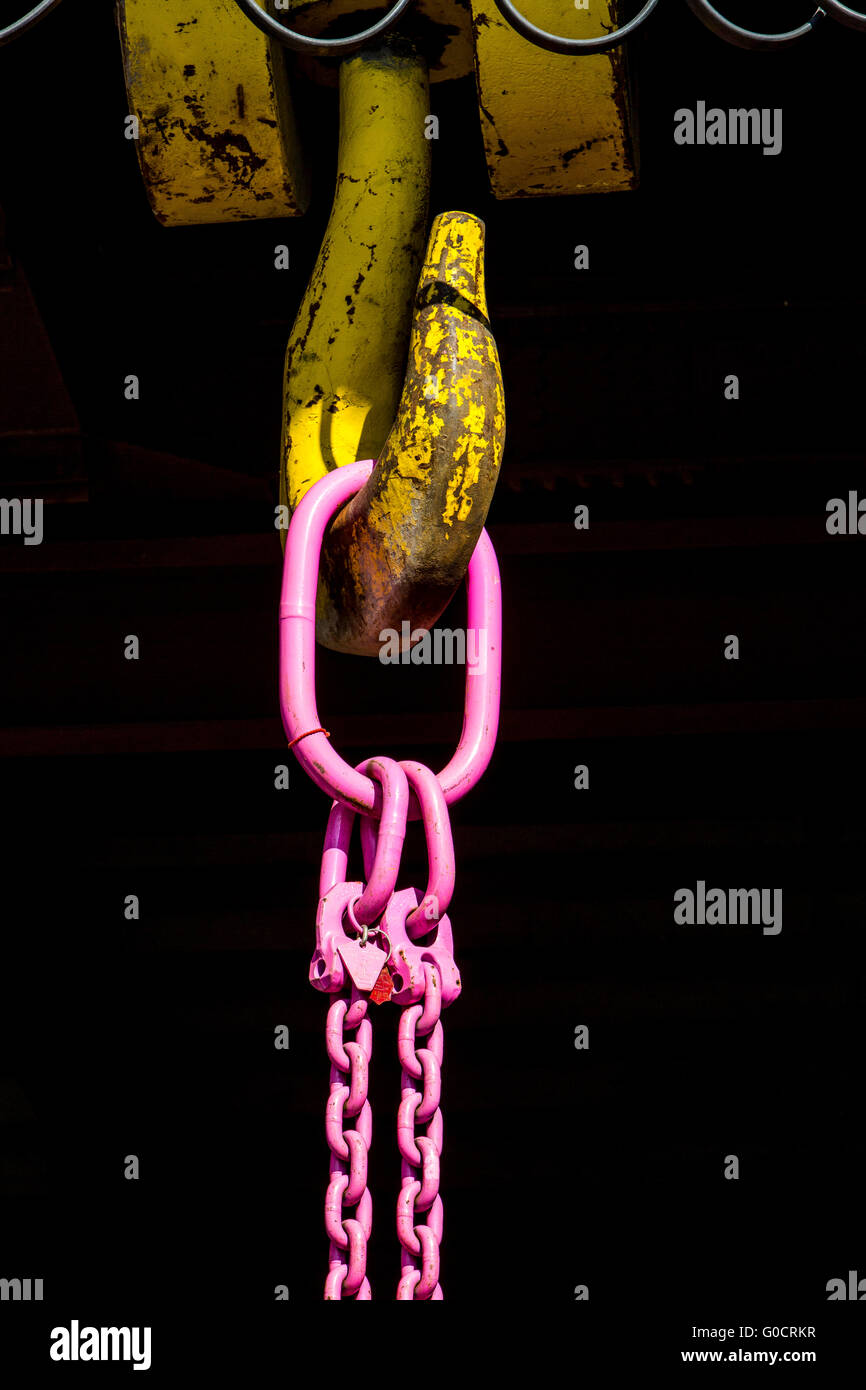 Crochet d'une grue industrielle, crochet double chaîne, peint rose, accroché sur le crochet jaune Banque D'Images