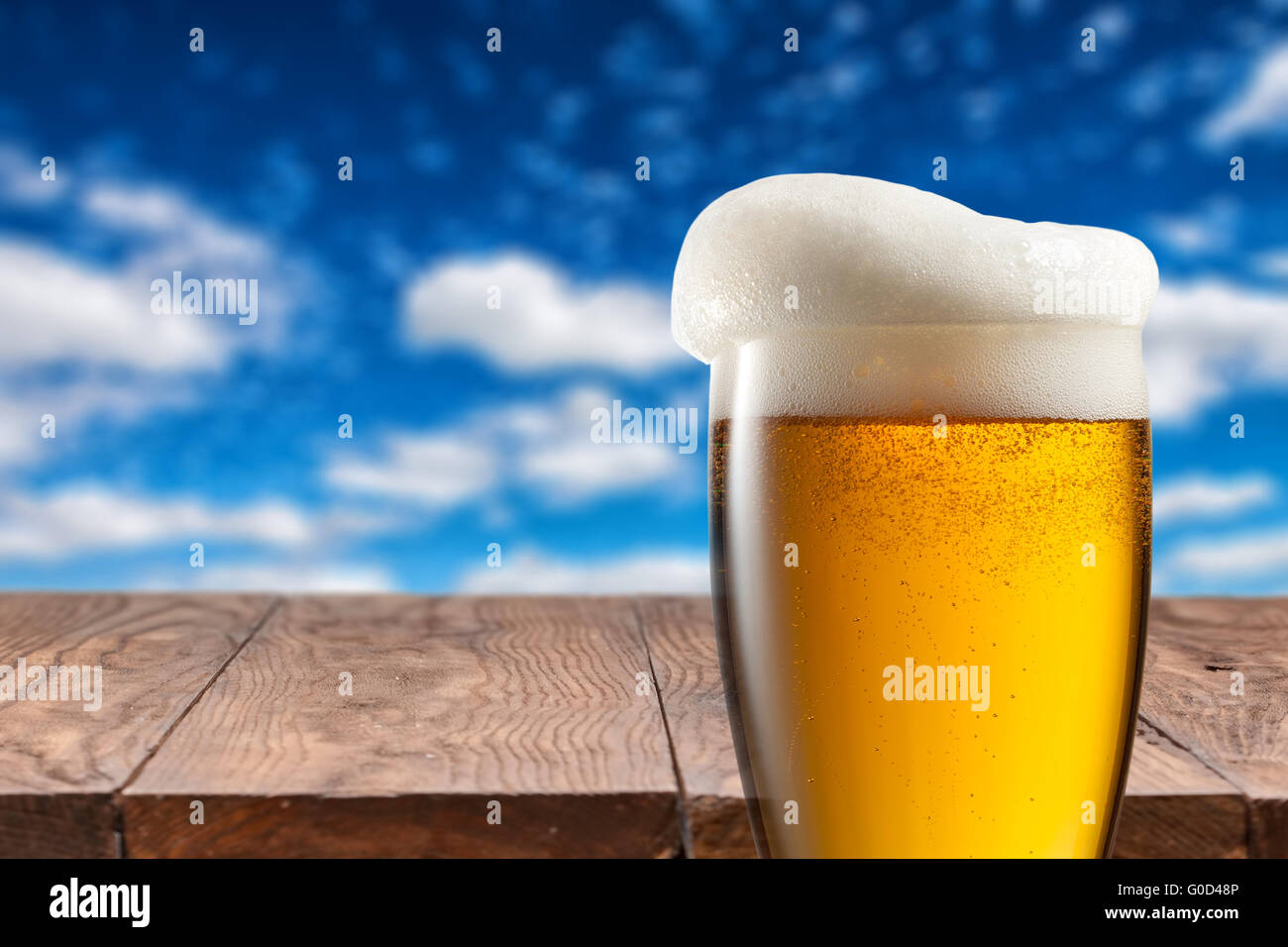 La bière dans le verre sur la table en bois contre le ciel bleu Banque D'Images