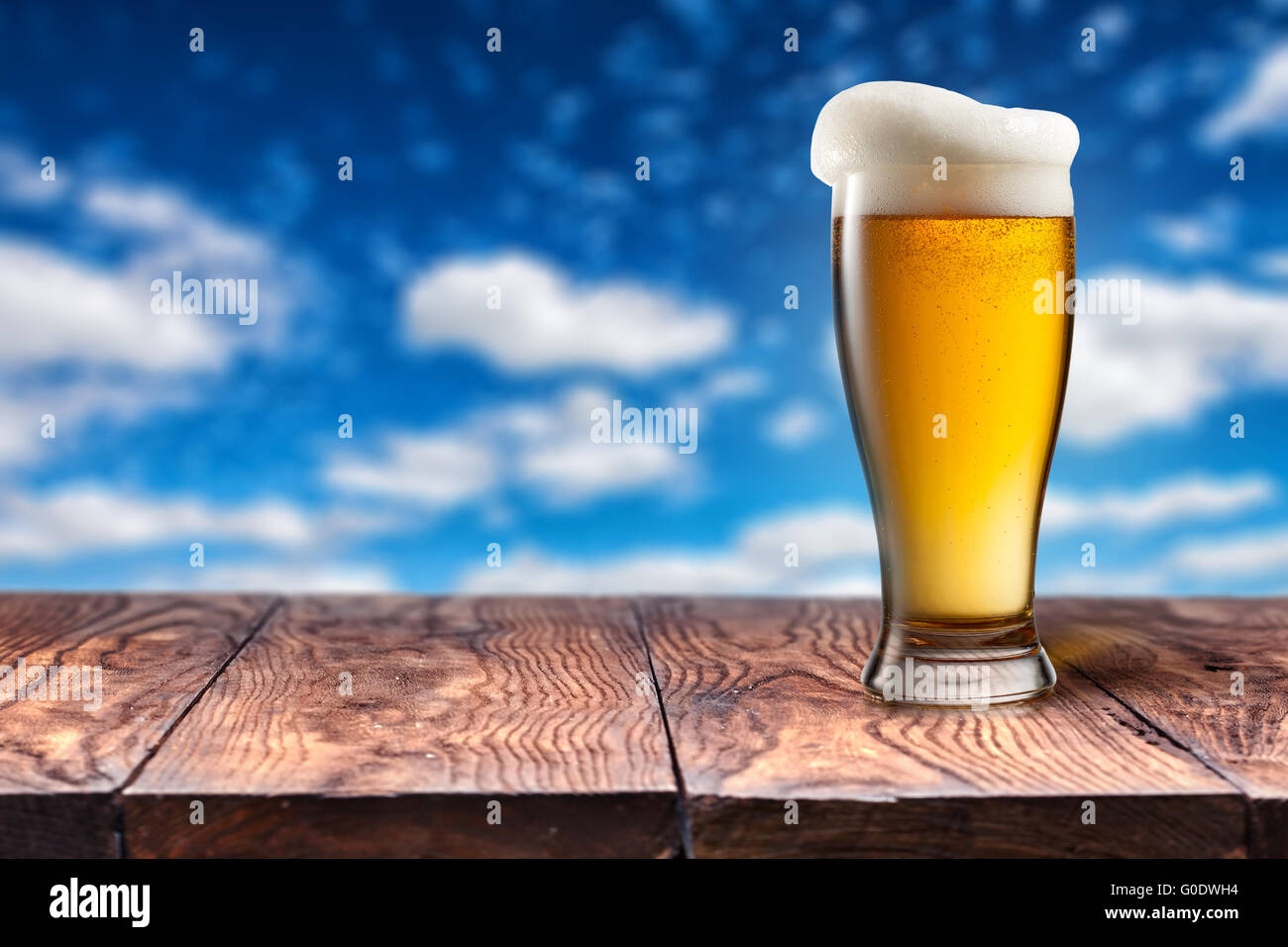 La bière dans le verre sur la table en bois contre le ciel bleu Banque D'Images