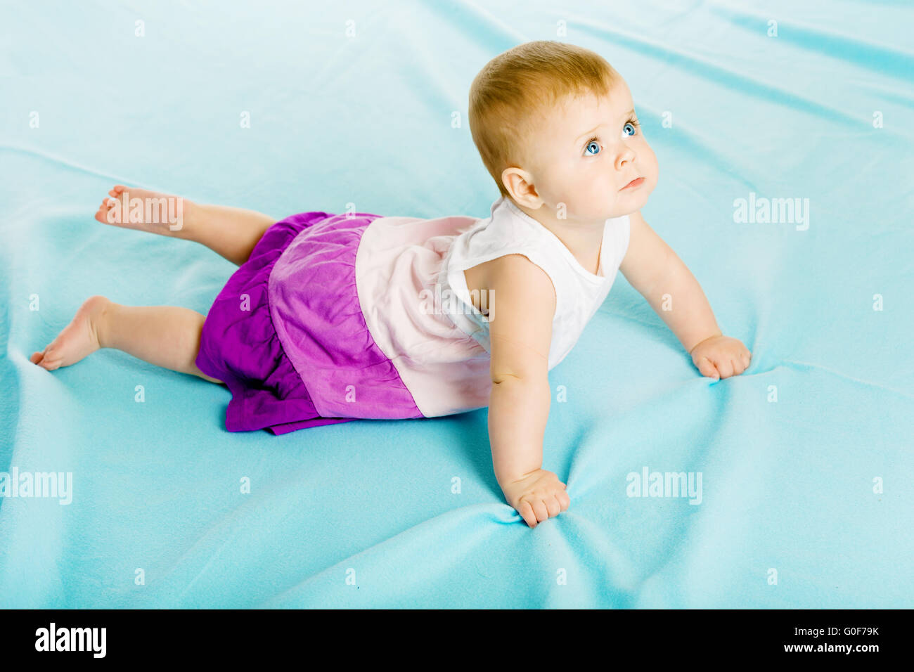 Robe bébé fille dans une rampe sur le couvre-lit bleu Banque D'Images