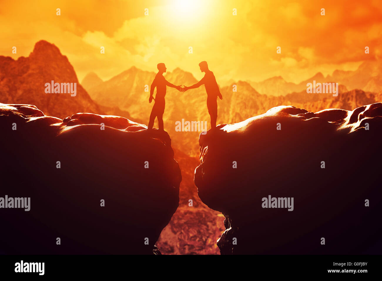 Deux hommes se serrent la main au-dessus du gouffre entre deux montagnes rocheuses au coucher du soleil. Business Banque D'Images